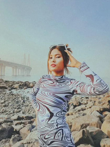 A fashion-forward portrait on the rocky shores of Bandra, with the Sea Link bridge providing a modern, graphic background.