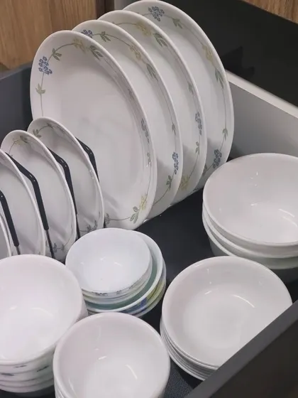 A drawer organized with daily-use Corelle dinnerware. Storing plates vertically in a rack prevents chipping and makes them easy to take out.
