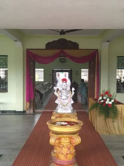 The entrance to a hall decorated with pink and yellow drapes and a central idol on a pedestal.