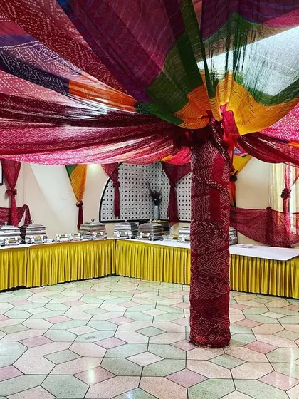 A vibrant, Rajasthani-themed buffet setup for a sangeet ceremony. The colourful bandhani drapes and traditional decor create a festive atmosphere for guests.