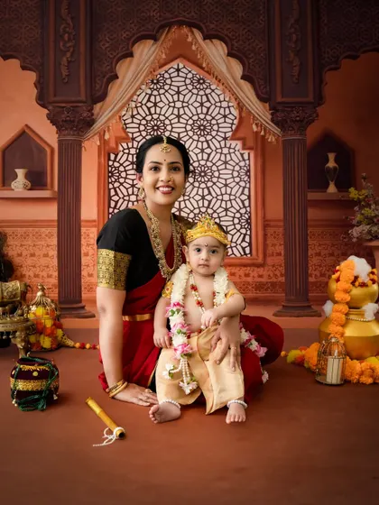 A classic seated portrait in front of a traditional Indian arch backdrop for a Janmashtami celebration.