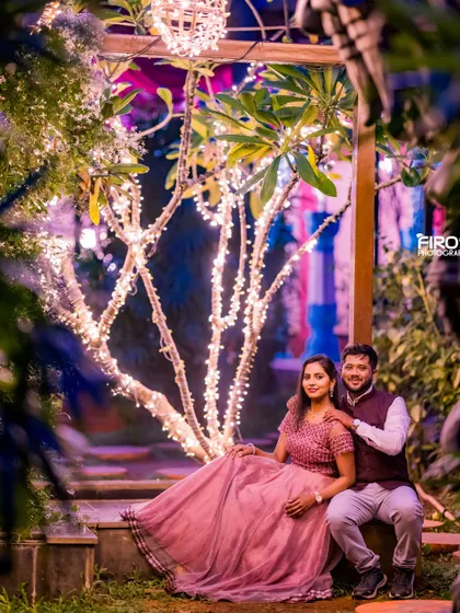 Seated together under a beautifully lit tree, this couple's portrait is filled with warmth and romance. The fairy lights provide a magical glow to the entire garden setting.
