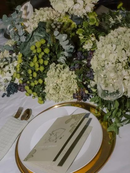 A close-up of the menu and place setting, surrounded by a lush arrangement of green hydrangeas and grapes.