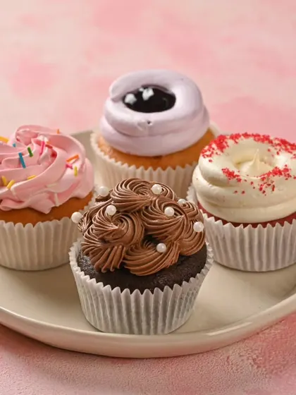 A simple plate of our assorted eggless cupcakes. We offer a variety of flavors like classic chocolate, strawberry sprinkle, red velvet, and blueberry, perfect for any craving or celebration.