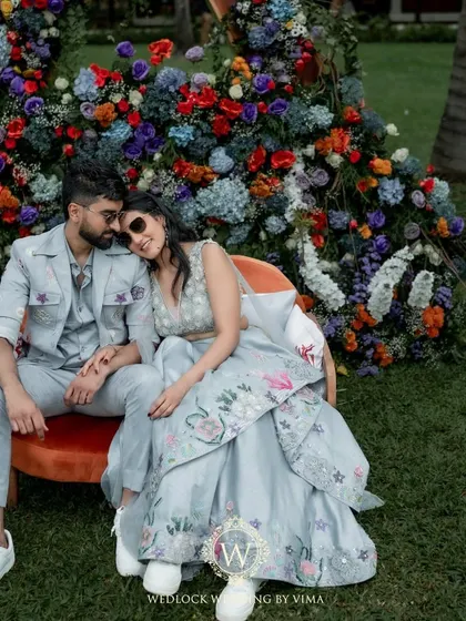 A quiet, happy moment between the couple at their colorful Mehendi ceremony. The vibrant floral backdrop perfectly frames their love and joy.