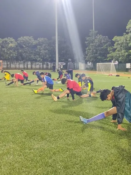 Our U13 players engaged in a strength and conditioning session, doing stretches under the stadium lights.