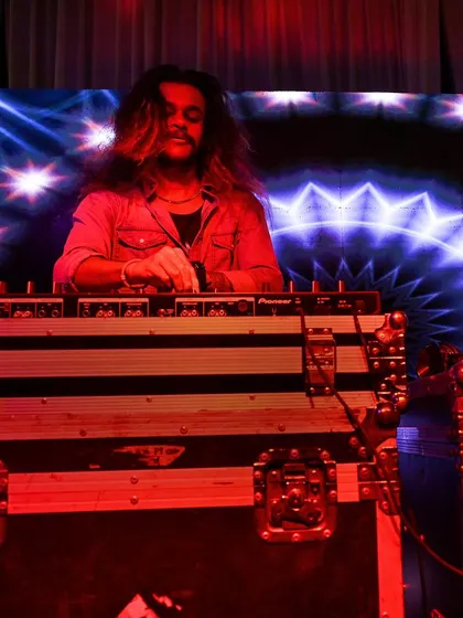 A shot of me at the decks, illuminated by red light and the glow of the LED screen behind me.