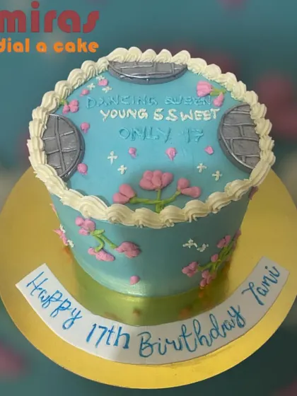 A lovely 17th birthday cake with a "Dancing Queen" theme. The light blue cake is decorated with delicate pink floral piping and vintage-style window details.