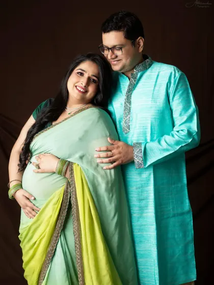 A lovely couple's portrait in soft, complementary colors. The mom-to-be's light green saree and the dad-to-be's aqua kurta create a fresh and happy look.