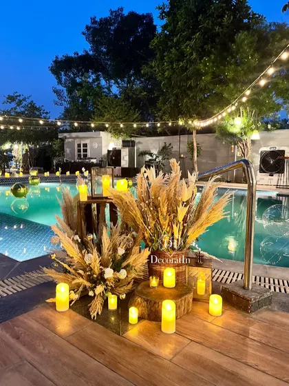 A beautiful corner by the pool, decorated with rustic wooden stumps, pampas grass arrangements, and candles, creating a serene and stylish spot.