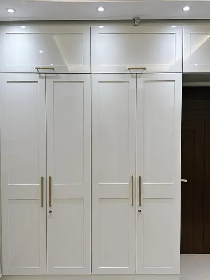 A beautiful example of a wardrobe that blends modern and Victorian design elements. The clean lines of the white shaker-style doors are complemented by elegant gold handles and classic wall moulding, creating a storage solution that is both highly functional and visually stunning.