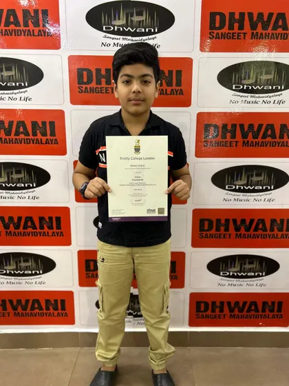 A young student proudly displays his Initial Grade certificate for Keyboard from Trinity College London. We prepare our students for internationally recognized music exams, providing a formal path for their skills.