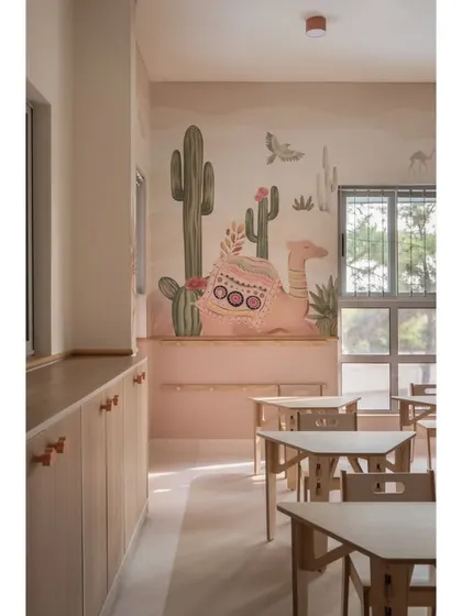 A close-up of the custom desert-themed wallpaper, featuring a friendly camel. The low-level wooden cabinets with custom knobs are designed for easy access for little hands, promoting independence and organization.