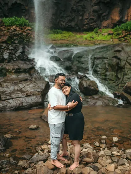 A full-length shot of a couple hugging by the waterfall, capturing their connection and the beautiful scenery.