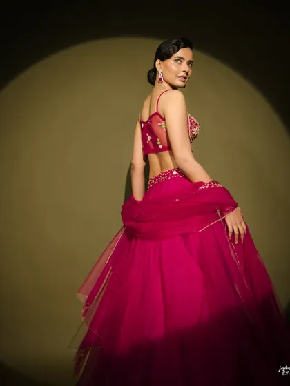 This back profile highlights the elegant hairstyle and the sheer back of the blouse. The updo is sleek and modern, perfect for this contemporary look.