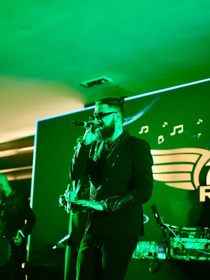 Our vocalist, lost in the music under the green stage lights. We perform with passion and give our all in every single song.