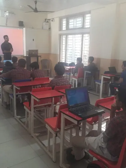 Students use their laptops to follow along with the instructor during a coding and cybersecurity workshop.