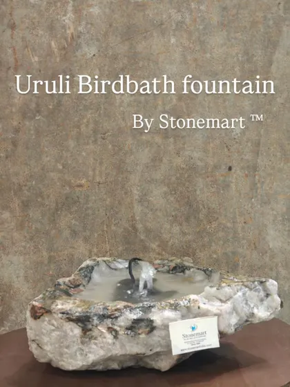 This unique piece is a tabletop fountain carved from a natural stone, giving it a rustic, organic look. It can function as an uruli bowl, a birdbath, or a small fountain.
