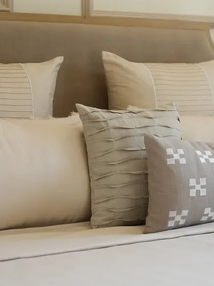 The soul of our work lies in the details. This close-up reveals the subtle textures, from delicate pintucks to geometric block prints, that define our neutral cushion collection, designed for an Alibaug villa.