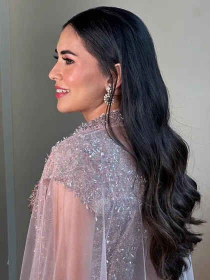 A profile view showcasing the soft waves and sparkling pink makeup. This look is perfect for a Sangeet, combining glamour with a touch of romance.