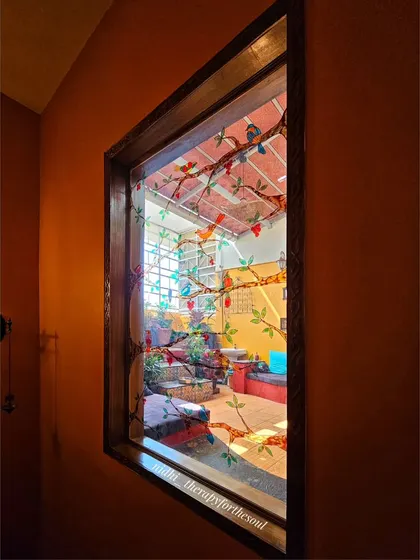 The finished glass painting installed in the terrace window, viewed from inside. It beautifully frames the view and adds a layer of color and artistry to the space.