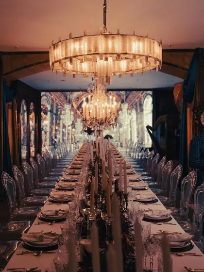 A breathtaking view of our tablescape for an event inspired by the Château de Versailles' Hall of Mirrors. The endless table, dramatic chandeliers, and warm candlelight created an opulent and truly immersive dining atmosphere.