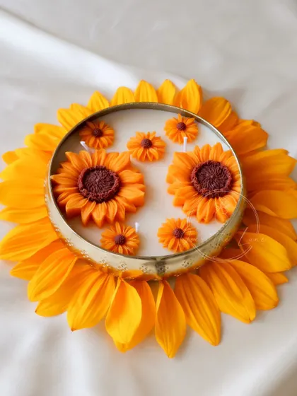 A top-down view of the Sunflower Urli, showing the arrangement of large and small sunflower wax melts within the brass bowl.