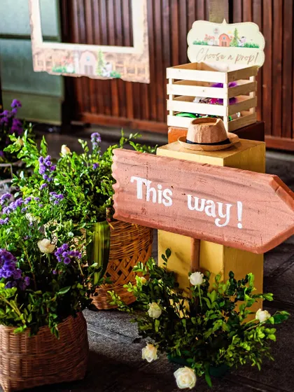 "This way to the fun!" A rustic photo booth corner with props and a charming hand-painted sign. This is a great way to encourage guests to take fun pictures.