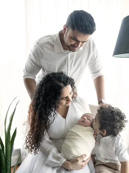 A family united in love for their new baby. This photo shows the gentle interaction between parents, a big brother, and the newborn, creating a heartwarming family portrait.