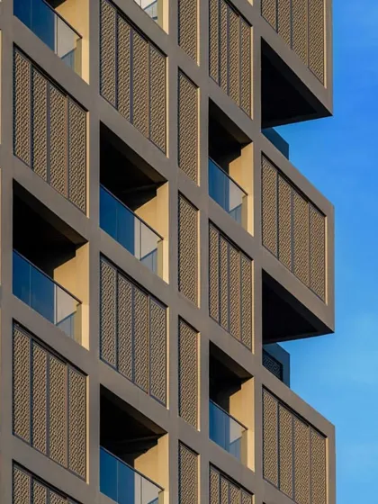 A detailed view of the perforated screens on the 'SCREEN 504' building. This project is a masterclass in using local stone and craftsmanship for modern, energy-efficient residential design.