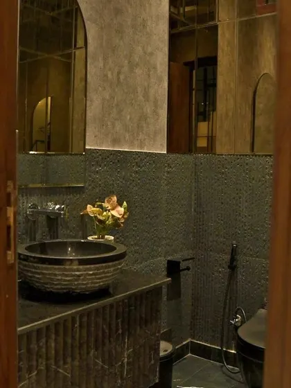 A closer look at the textured sink and the elegant bronze mirror panels that add depth and luxury to the space.