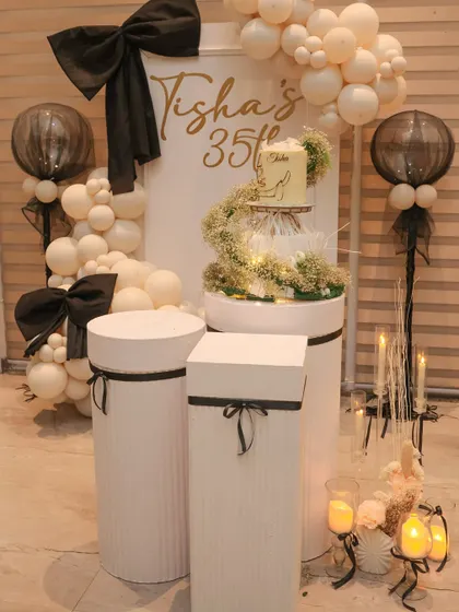 The complete cake station for the bow-themed party, including the backdrop, cake plinths, and candle arrangements.