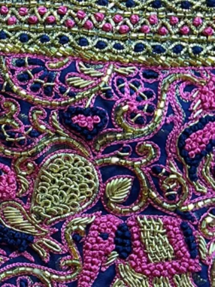 A macro shot of the intricate embroidery, highlighting the different stitches and textures used to create the peacock and floral patterns.