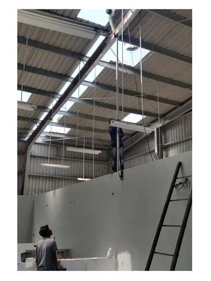 The team at work installing lighting and ceiling components within the industrial metal roof structure, a key step in transforming the warehouse into a functional office.