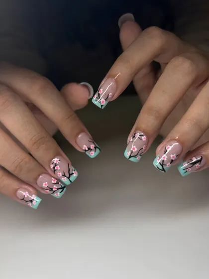 A beautiful cherry blossom nail art design. This set features a mint green French tip with hand-painted cherry blossom branches on a sheer nude base.