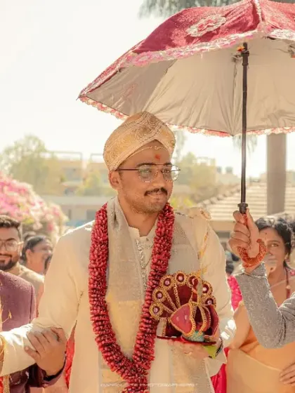 The groom's happy entrance under a traditional decorated umbrella. His smile shows the excitement and joy of the moment.