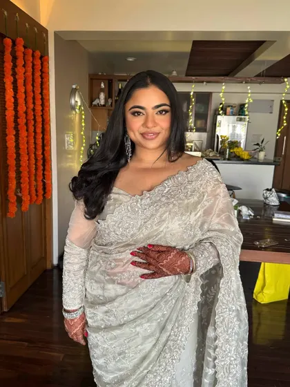 A lovely portrait of our bride in a silver saree. Her makeup is sophisticated and radiant, with soft waves in her hair completing the elegant look.