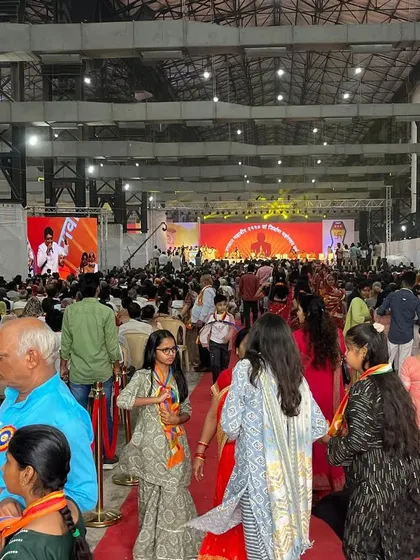 A wide shot of the massive crowd inside the Nesco exhibition center for Lord Mahavir's foundation day celebration. Our team is experienced in managing logistics for thousands of attendees in large venues.
