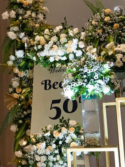 Another angle of the welcome area for the 50th birthday. The arrangement of floral displays and gold pedestals created a beautiful, layered look that guided guests into the main party space.