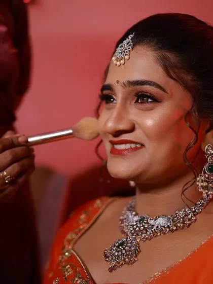 A happy moment during the makeup process for Hamsa's reception. A light dusting of powder sets the look, ensuring it stays perfect all night long.