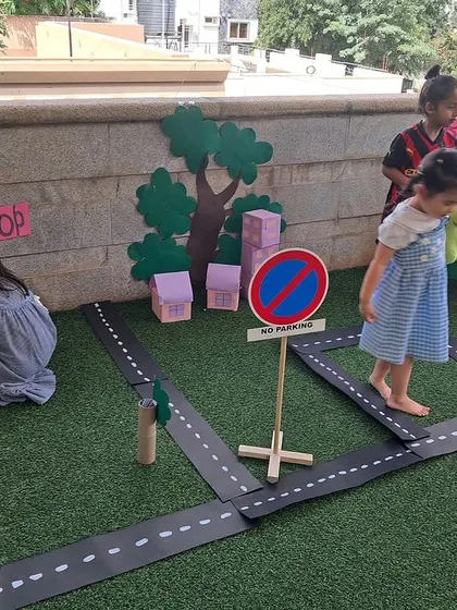 Children interact with different parts of the community, including a vegetable shop and road signs. This detailed setup encourages complex narratives and social interactions.