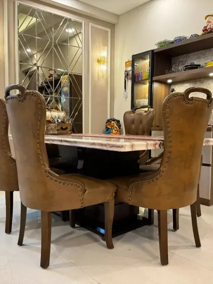 A luxurious dining setup from a Gurgaon project, featuring high-back studded leather chairs and a marble-top table, perfect for elegant family dinners.