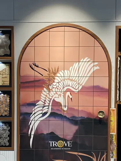 This custom tile mural of a crane in flight, set against a warm, dusky sky, brings a sense of grace and artistry to the space. The arched frame adds an architectural element, making it feel like a unique piece of installed art.