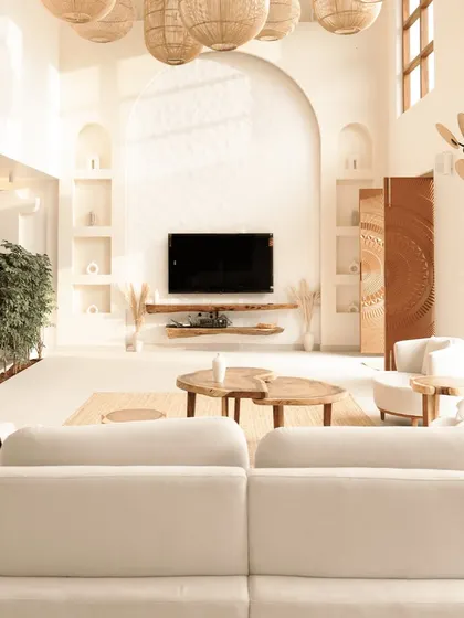 The main living area is defined by its soaring ceilings and an arched feature wall with built-in niches for curated decor. The design emphasizes natural light and an uncluttered aesthetic, making the large space feel serene and grounded.