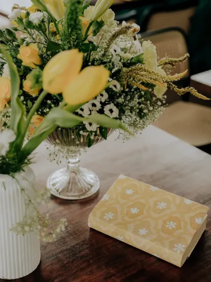 A delicate floral arrangement in a crystal vase, paired with custom-printed stationery, showing how I coordinate all visual elements of an event.