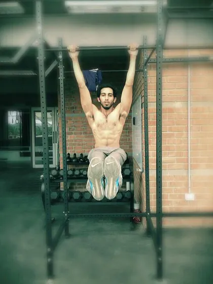 A classic L-sit pull-up hold. This is an advanced calisthenics exercise that requires significant core and back strength.