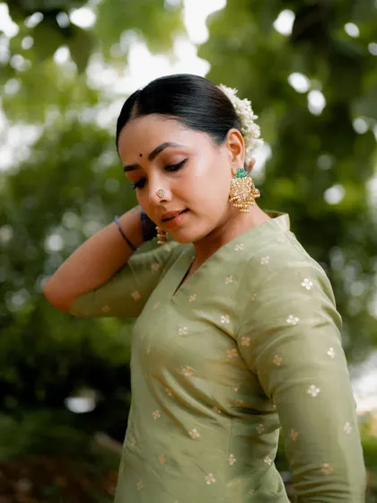 A candid portrait of an actress in a simple yet elegant green kurta. The natural outdoor lighting and relaxed pose create an authentic and relatable image for a lifestyle brand.