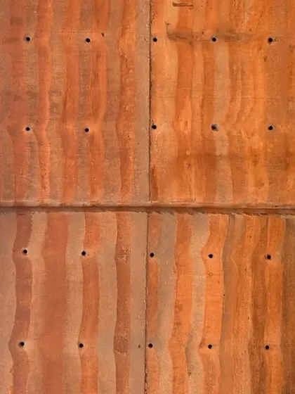 This section of rammed earth has a more vertical, wood-grain-like texture, showing the versatility of the technique.