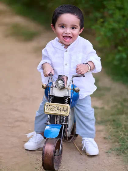 The pure excitement of a first birthday photoshoot. This little boy's joyful expression says it all as he gets ready to take his toy motorcycle for a spin.