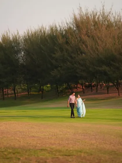 A stunning landscape shot of a couple in a sprawling green field, emphasizing the beauty of the location.